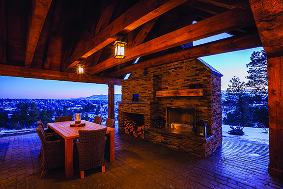 The timber trusses in this outdoor living space are structural as well as decorative. The wood burning fireplace has a wood beam mantle and stamped concrete hearth done by Smitty’s Fireplace Shop. Photo by Nicole Keintz